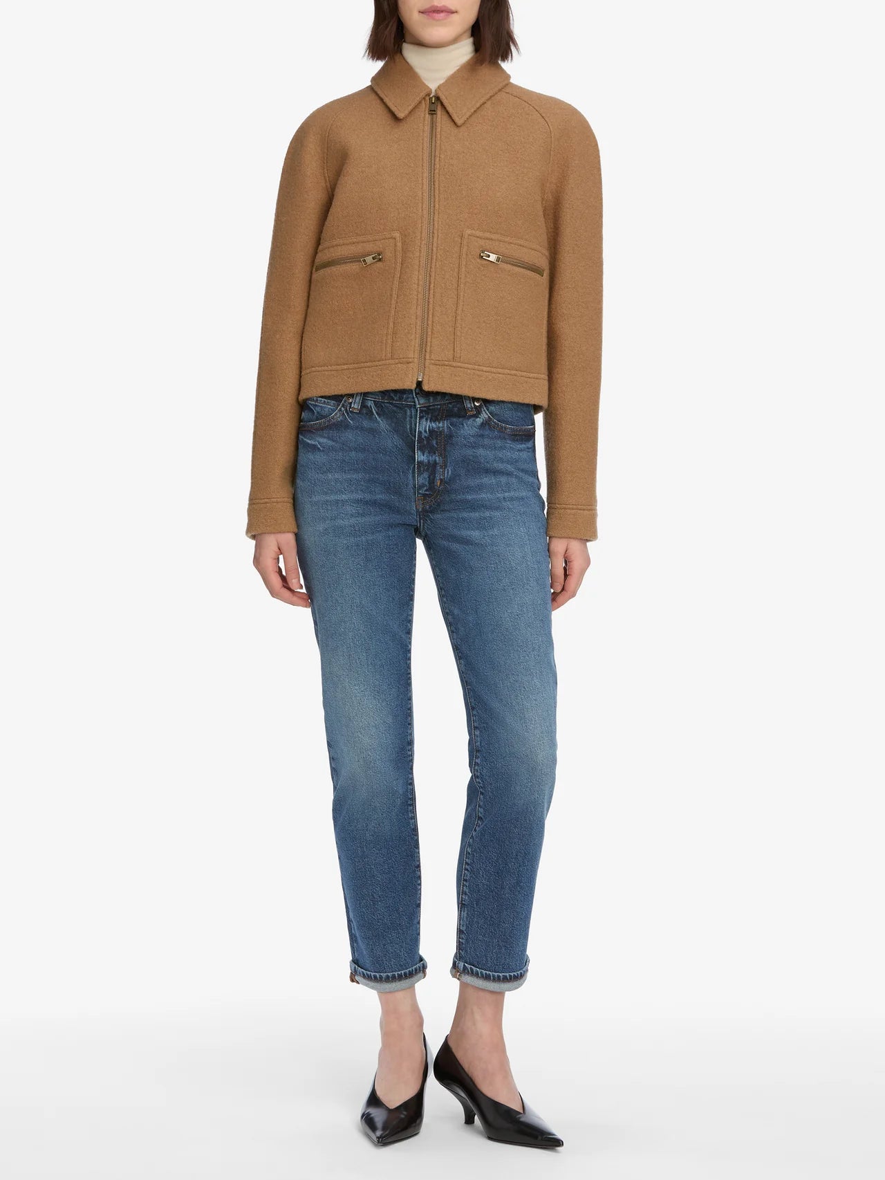 Person wearing a brown jacket and blue jeans on a white background