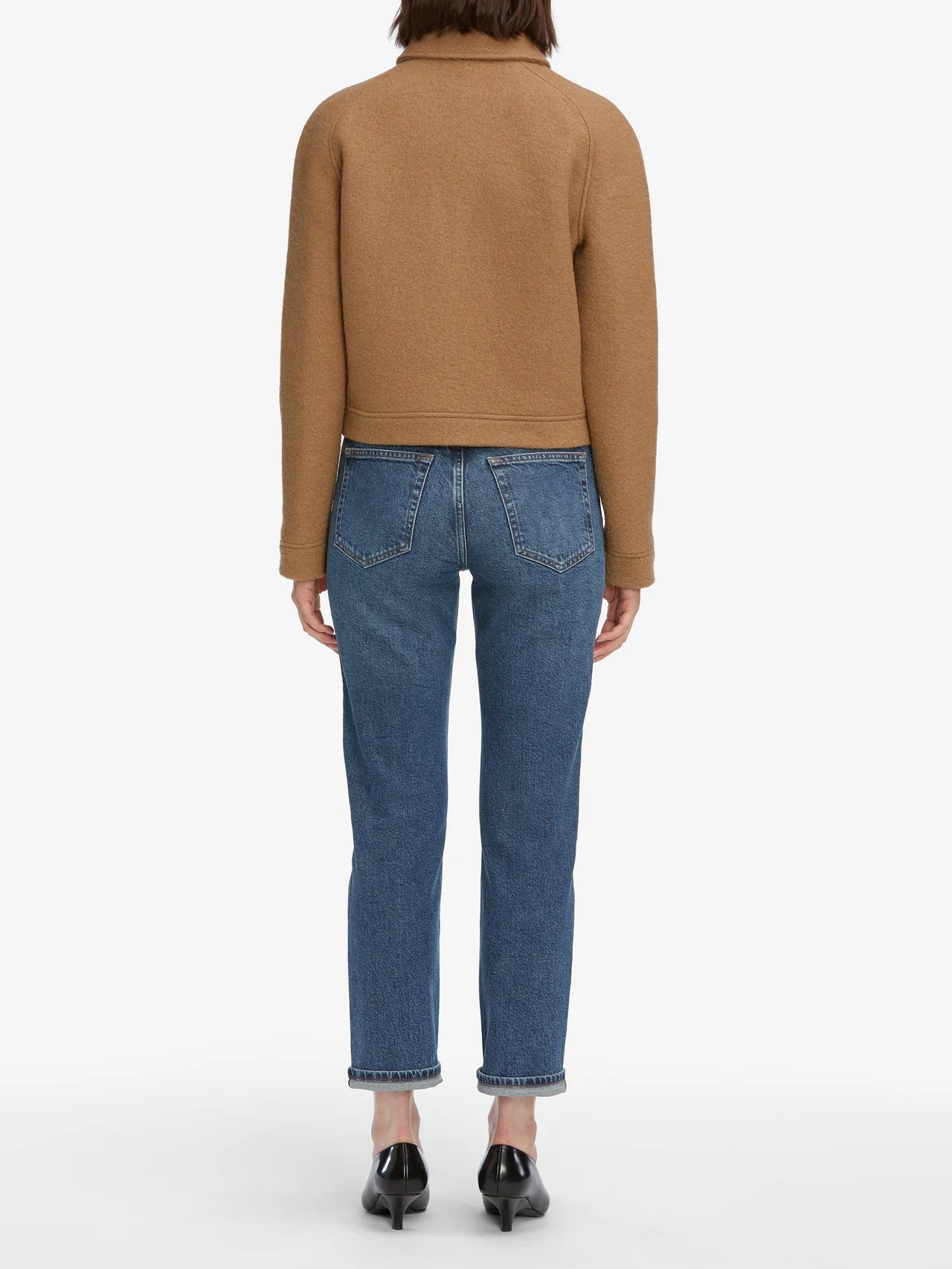 Person wearing a brown sweater and blue jeans on a white background