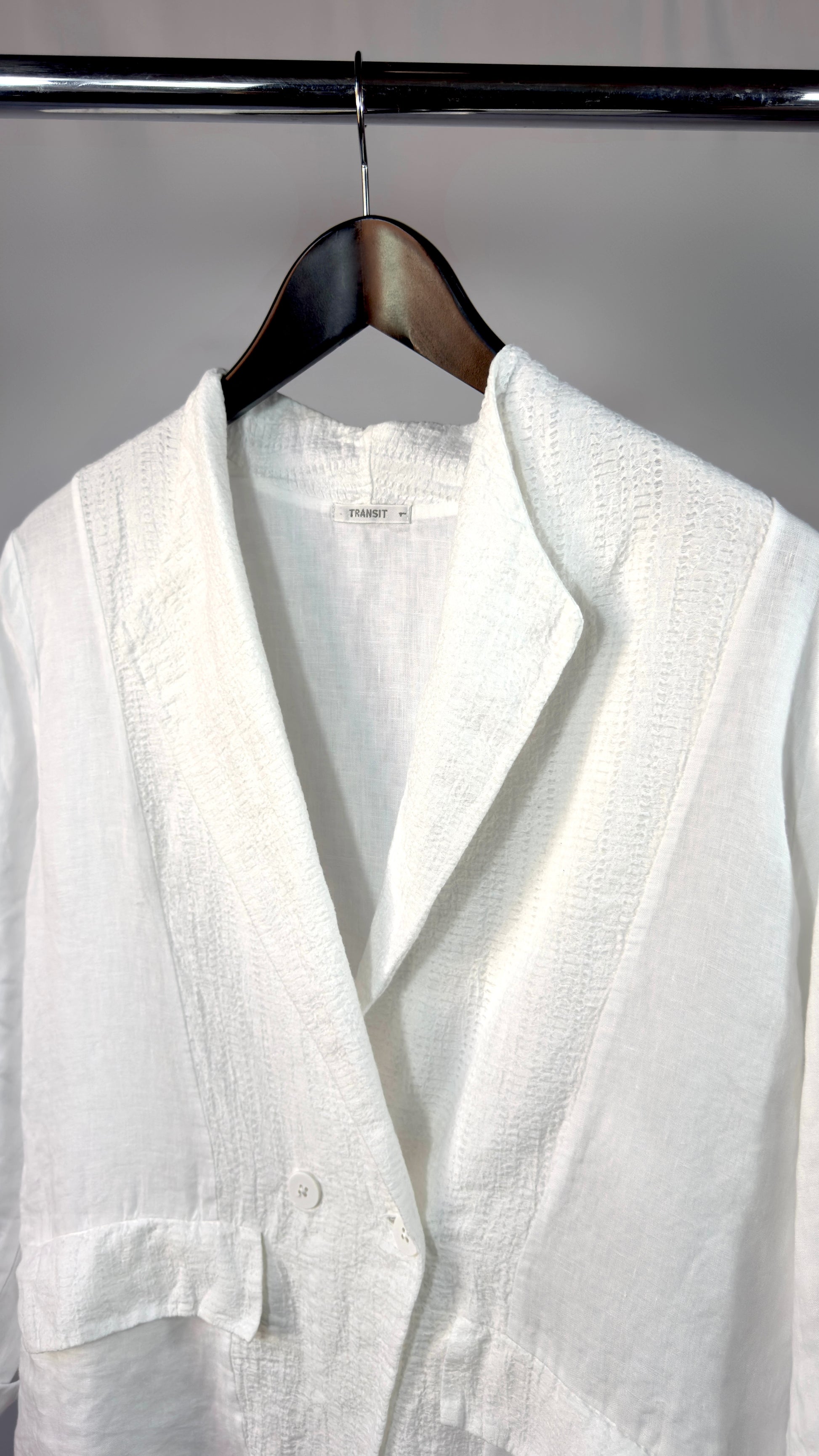 White linen shirt on a hanger against a gray background