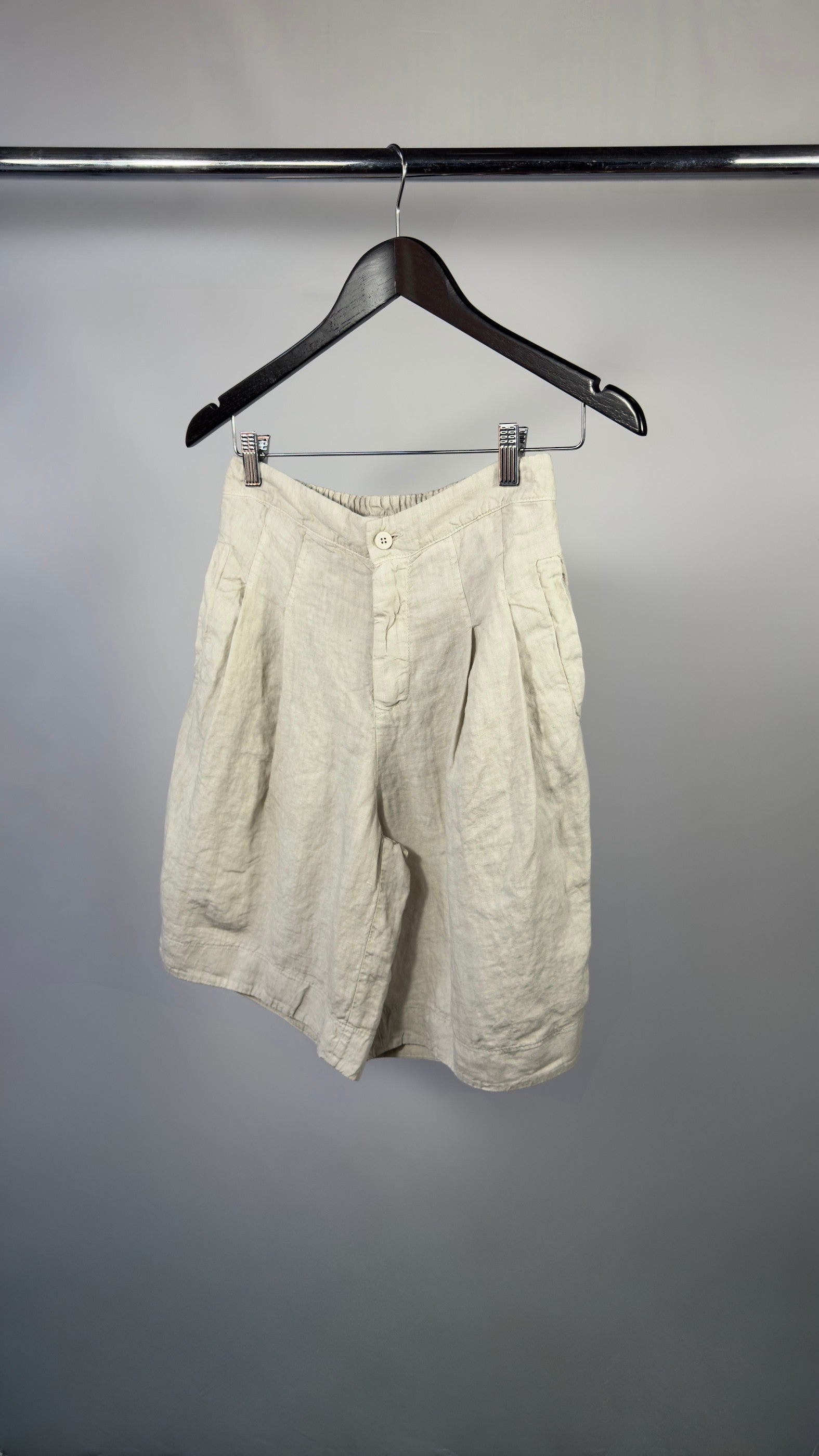 Beige shorts on a hanger against a plain background