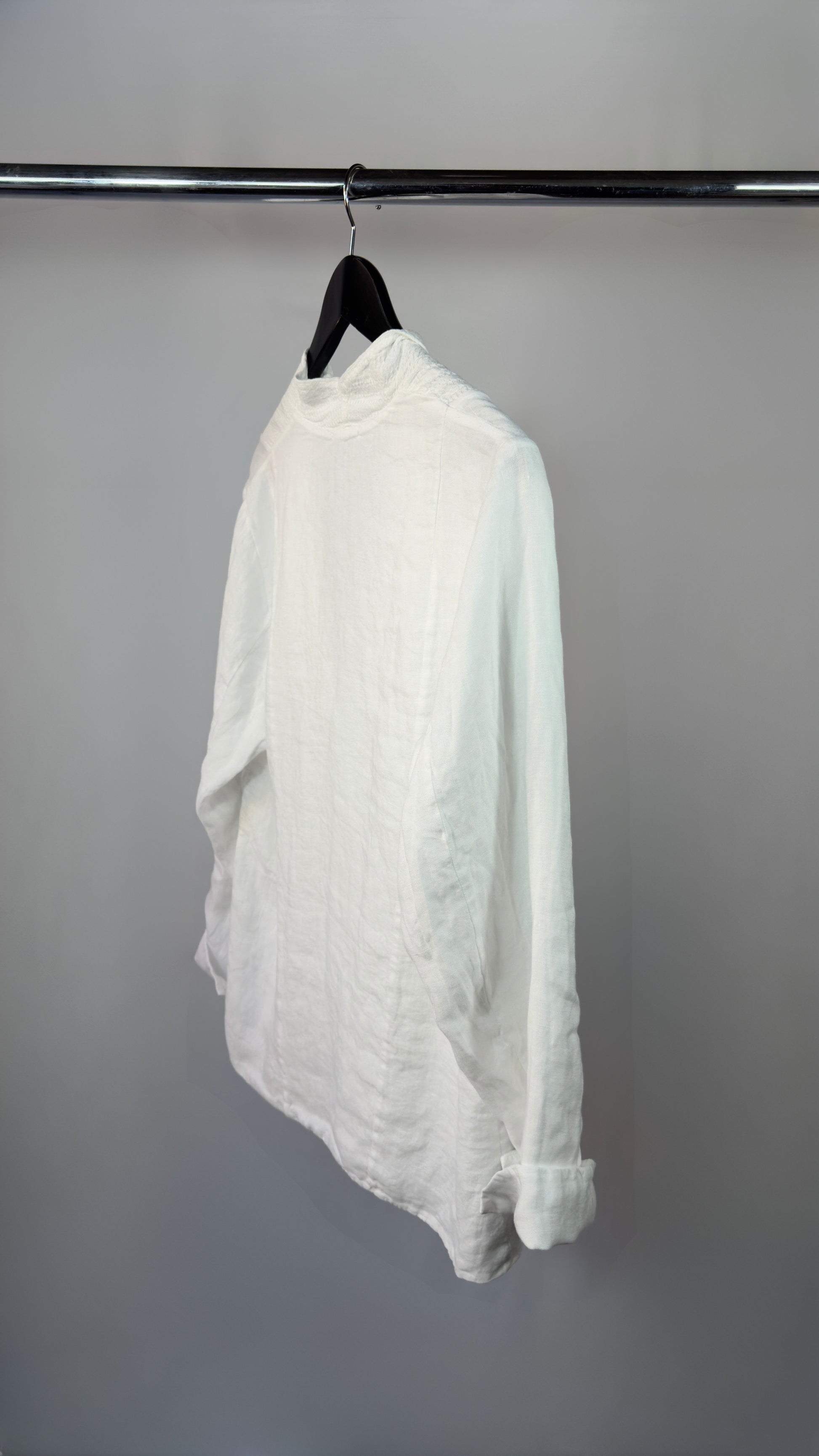 White shirt hanging on a black hanger against a gray background