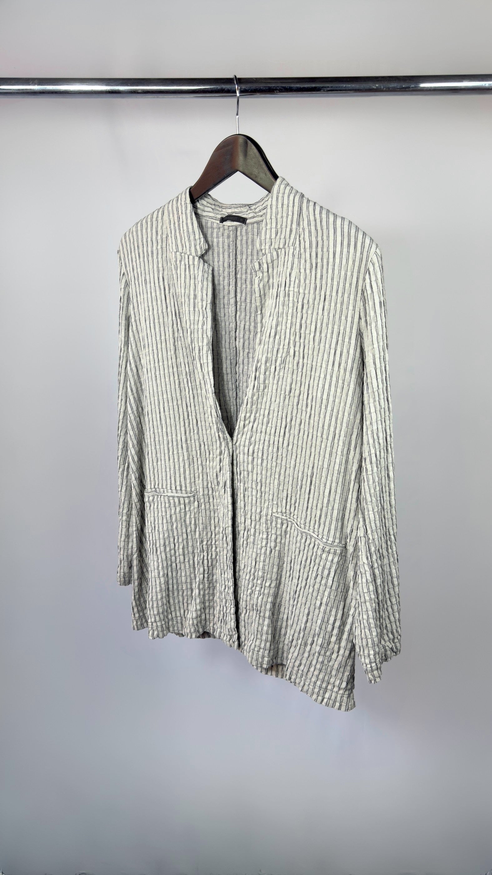 Green and white striped shirt on a hanger against a plain background