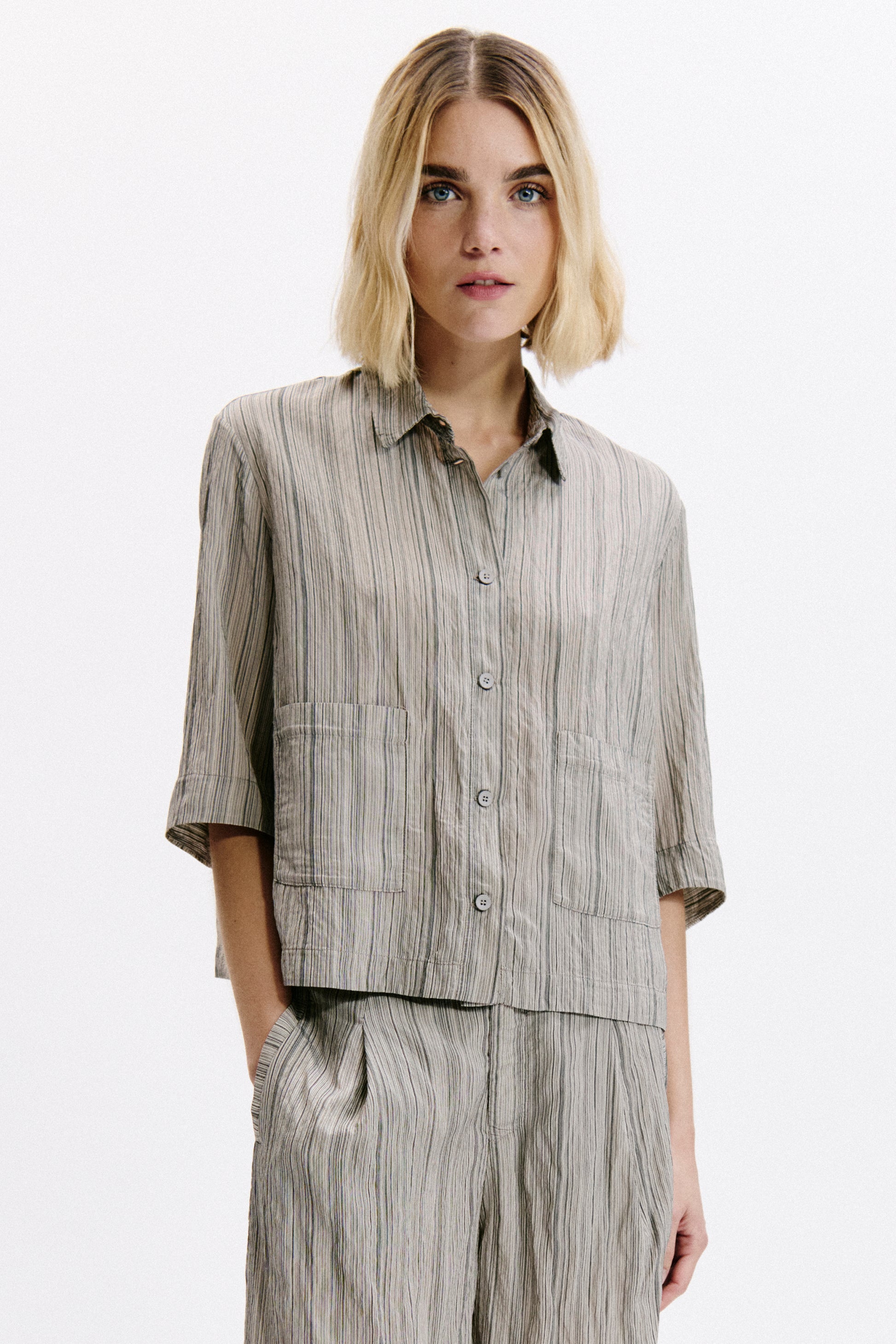 Woman wearing a matching striped shirt and pants set on a white background