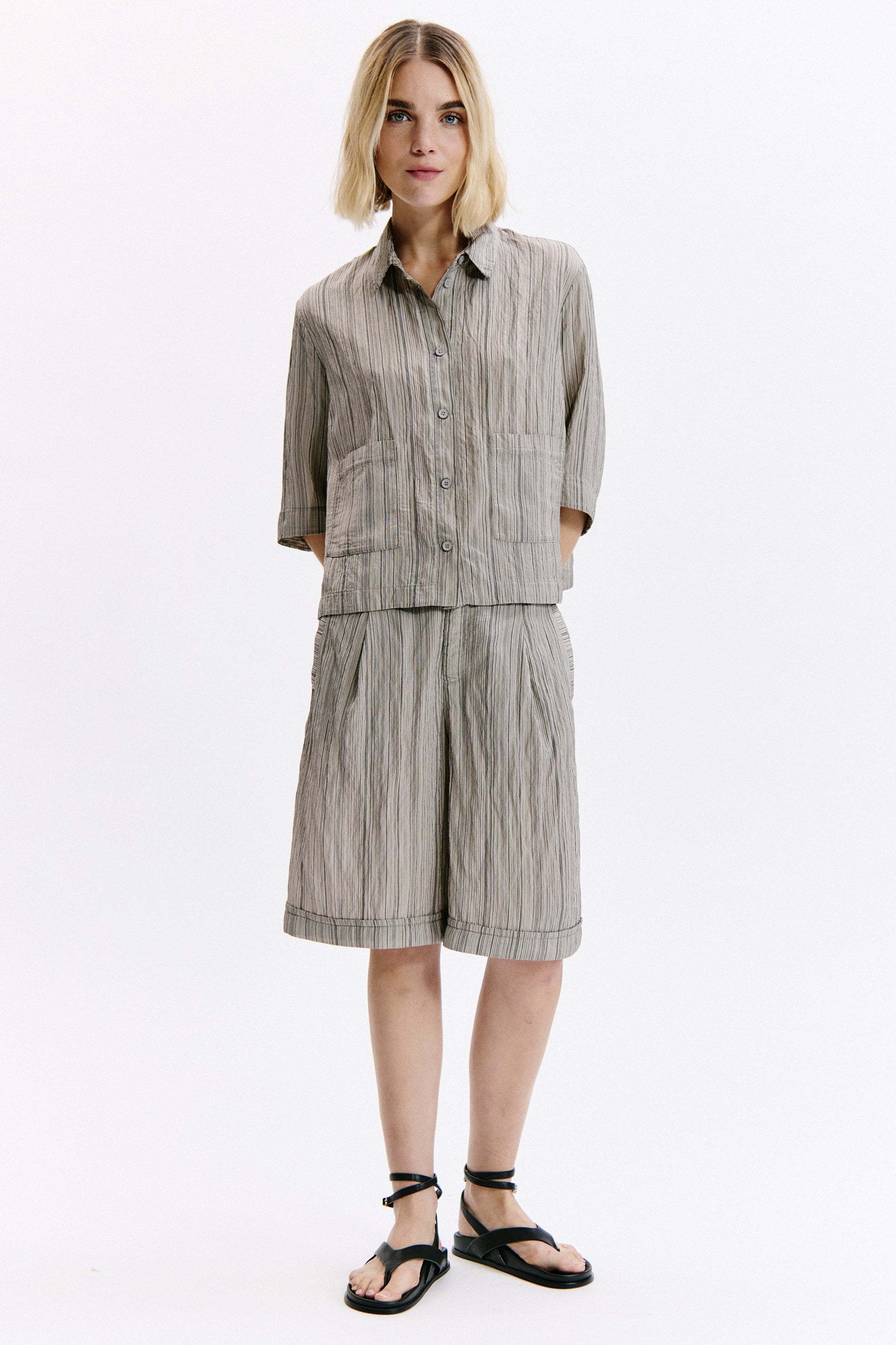 Woman wearing a gray striped dress on a white background