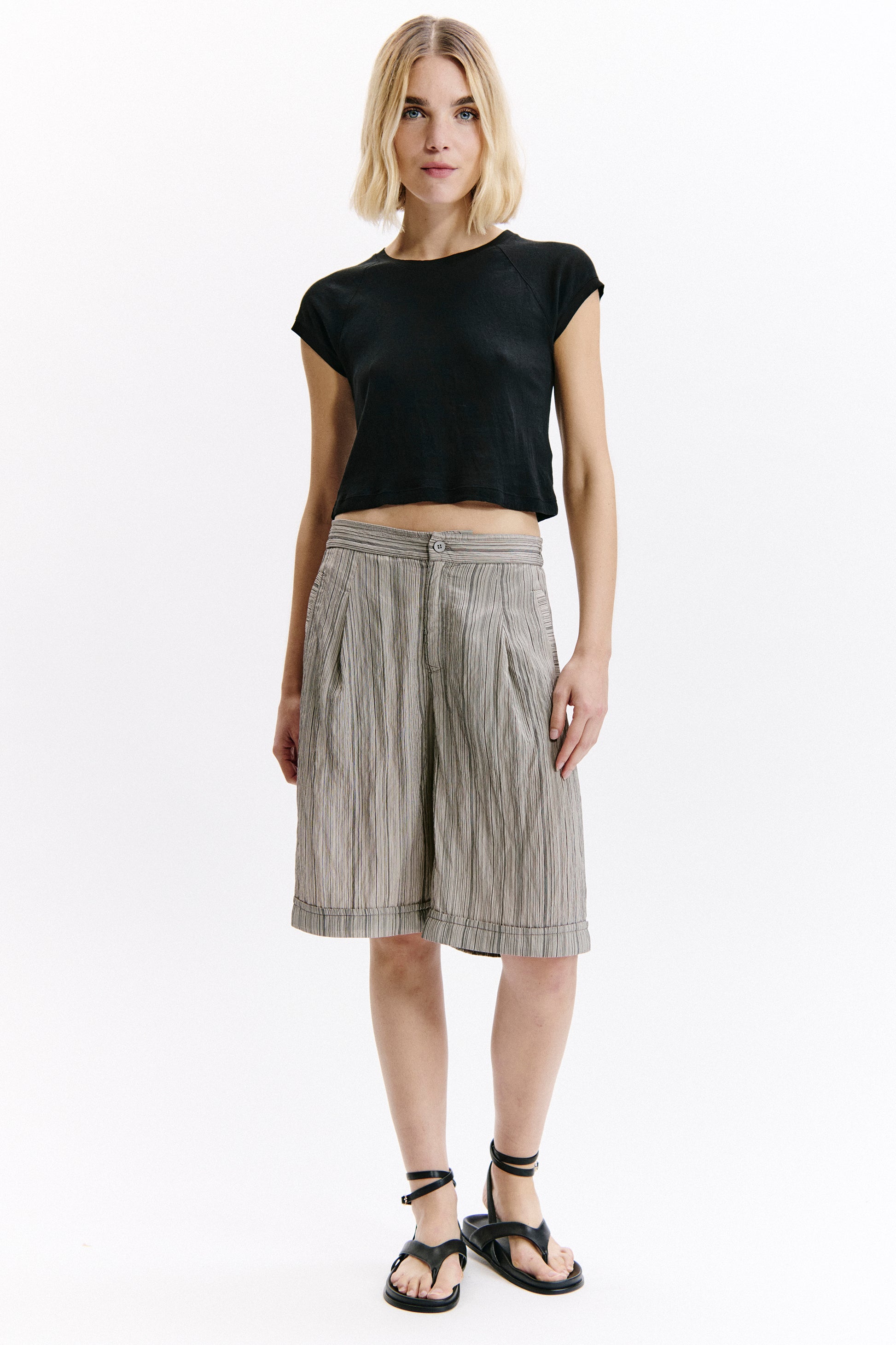 Woman wearing a black top and striped skirt on a white background