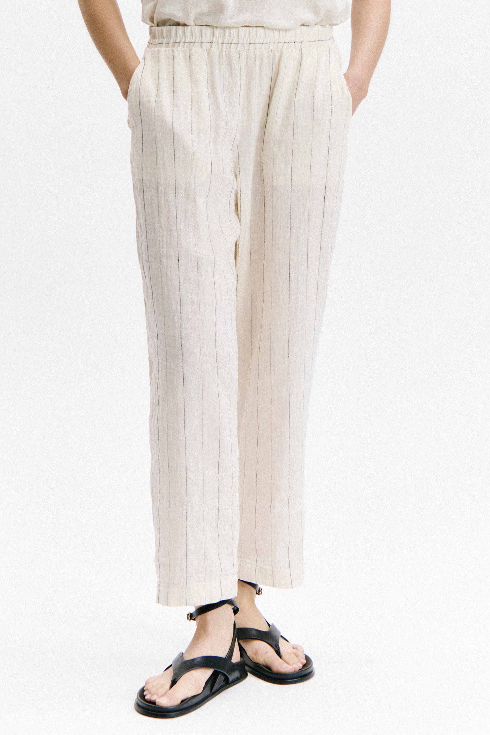 Person wearing white pleated pants on a white background