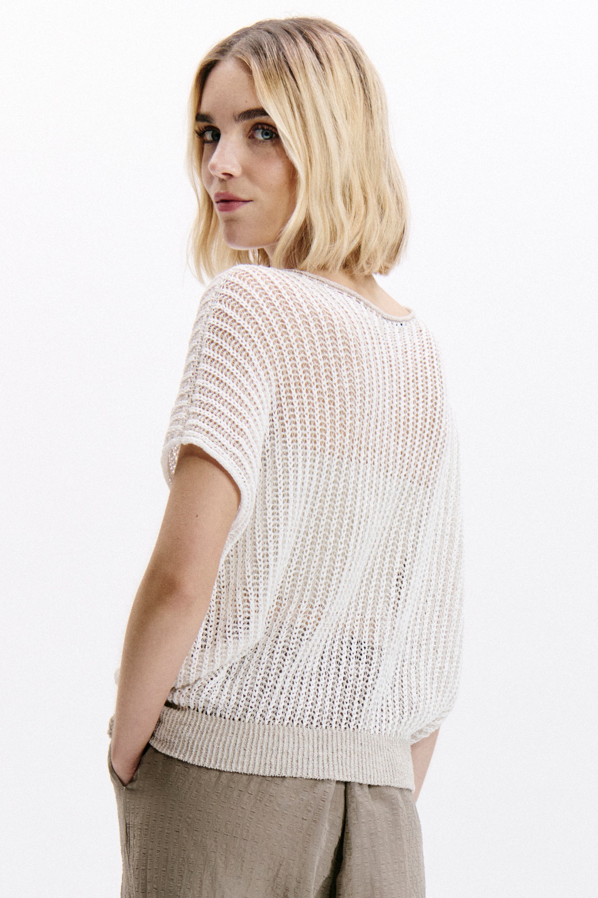 Woman wearing a light-colored knit top against a white background
