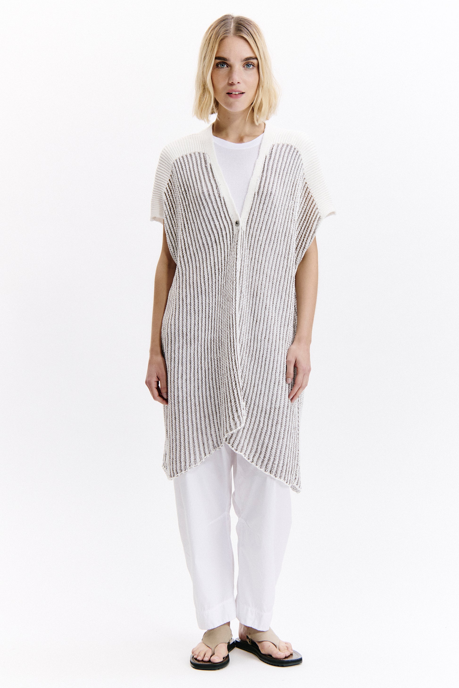 Woman wearing a black and white striped vest over a white shirt on a white background