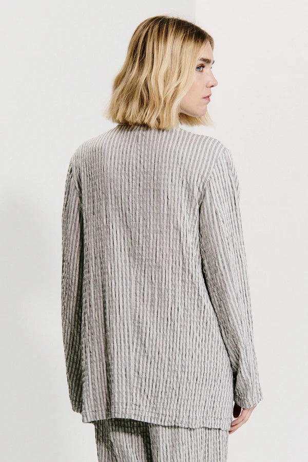 Person wearing a gray checkered outfit on a plain background