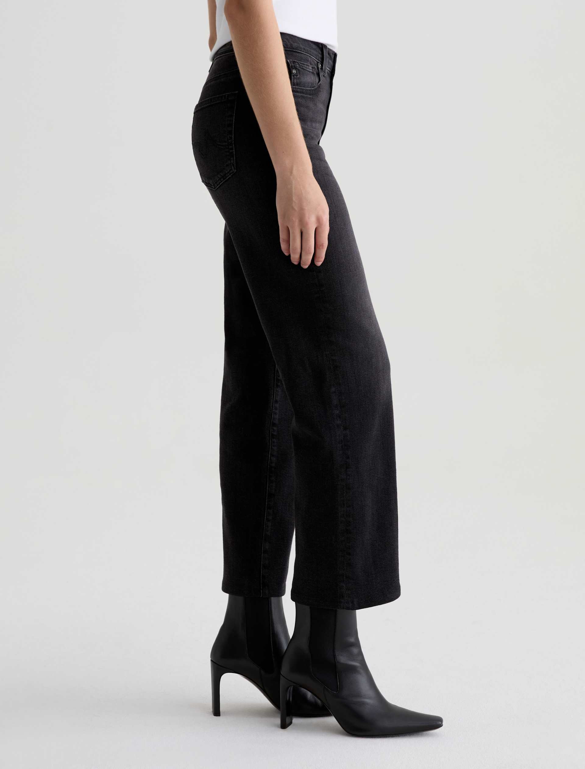 Person wearing black high-waisted jeans and black boots on a white background