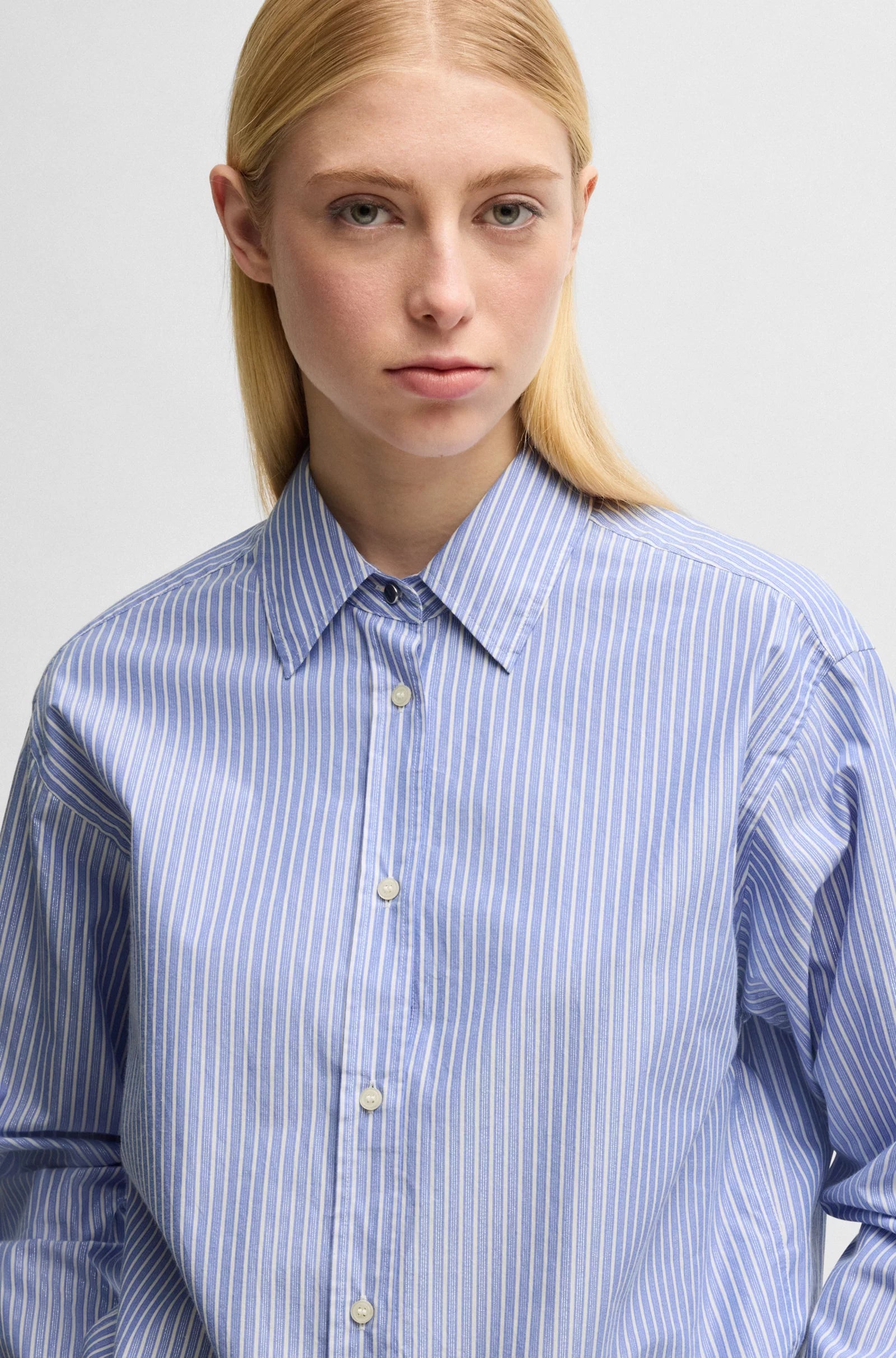 A woman wearing a relaxed-fit striped cotton-blend poplin blouse in orange, with a point collar, long sleeves, and button cuffs.