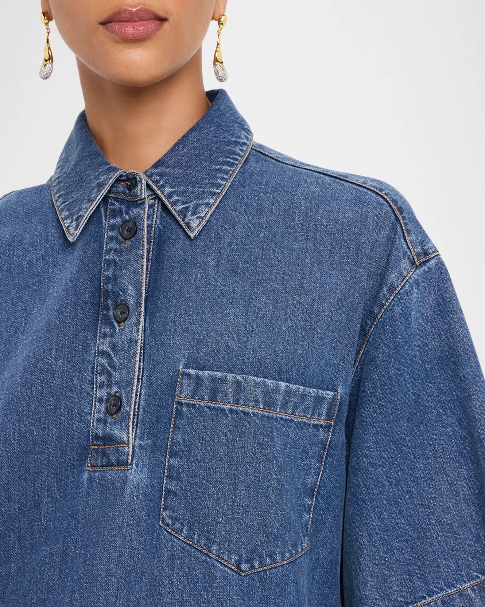 Close-up of a person wearing a blue denim shirt with a collar and pocket.