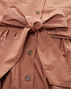 Close-up of a brown jacket with a bow detail and button details.