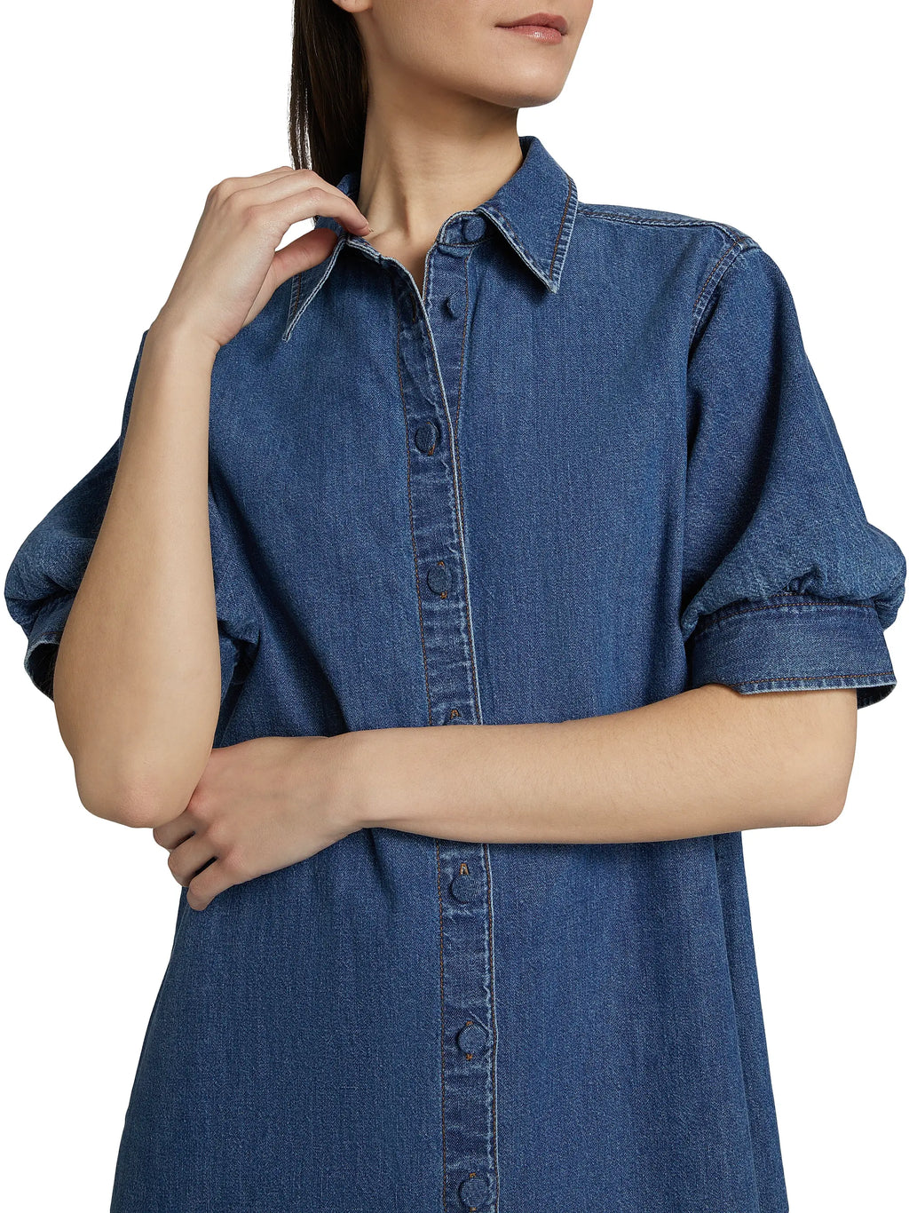 Woman wearing a blue denim dress with a plain background