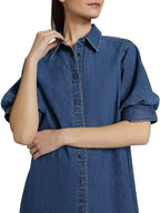 Woman wearing a blue denim dress with a plain background