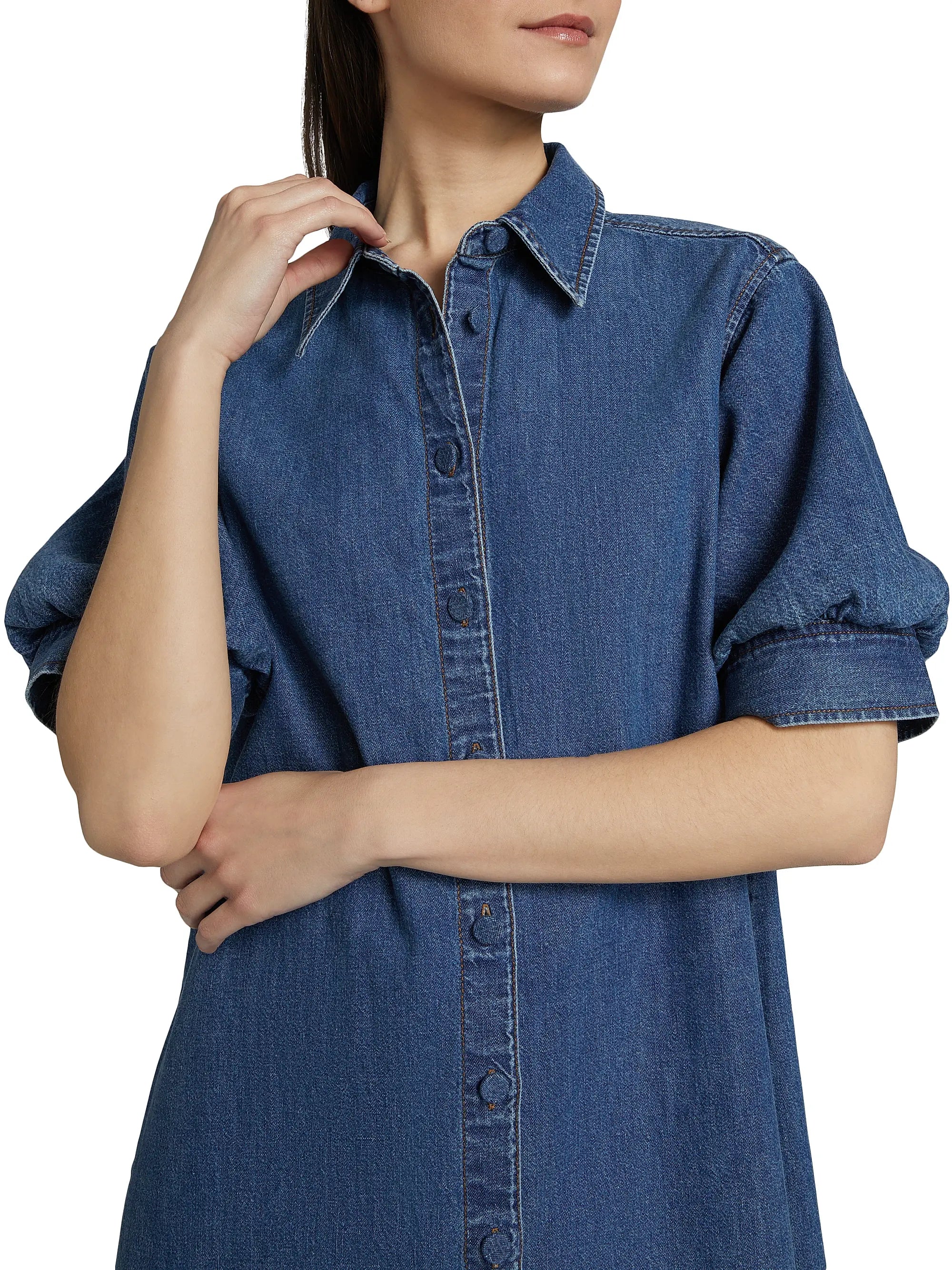 Woman wearing a blue denim dress with a plain background