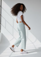 Woman wearing light blue jeans and a white t-shirt in a bright room.
