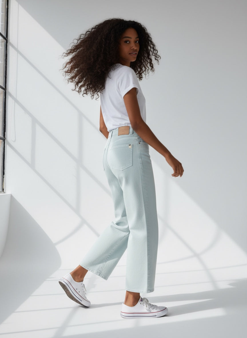 Woman wearing light blue jeans and a white t-shirt in a bright room.