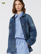 Woman wearing a blue denim jacket over a striped shirt on a white background