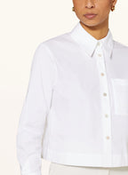 A woman wearing a white, long-sleeved, button-up shirt with a collar.