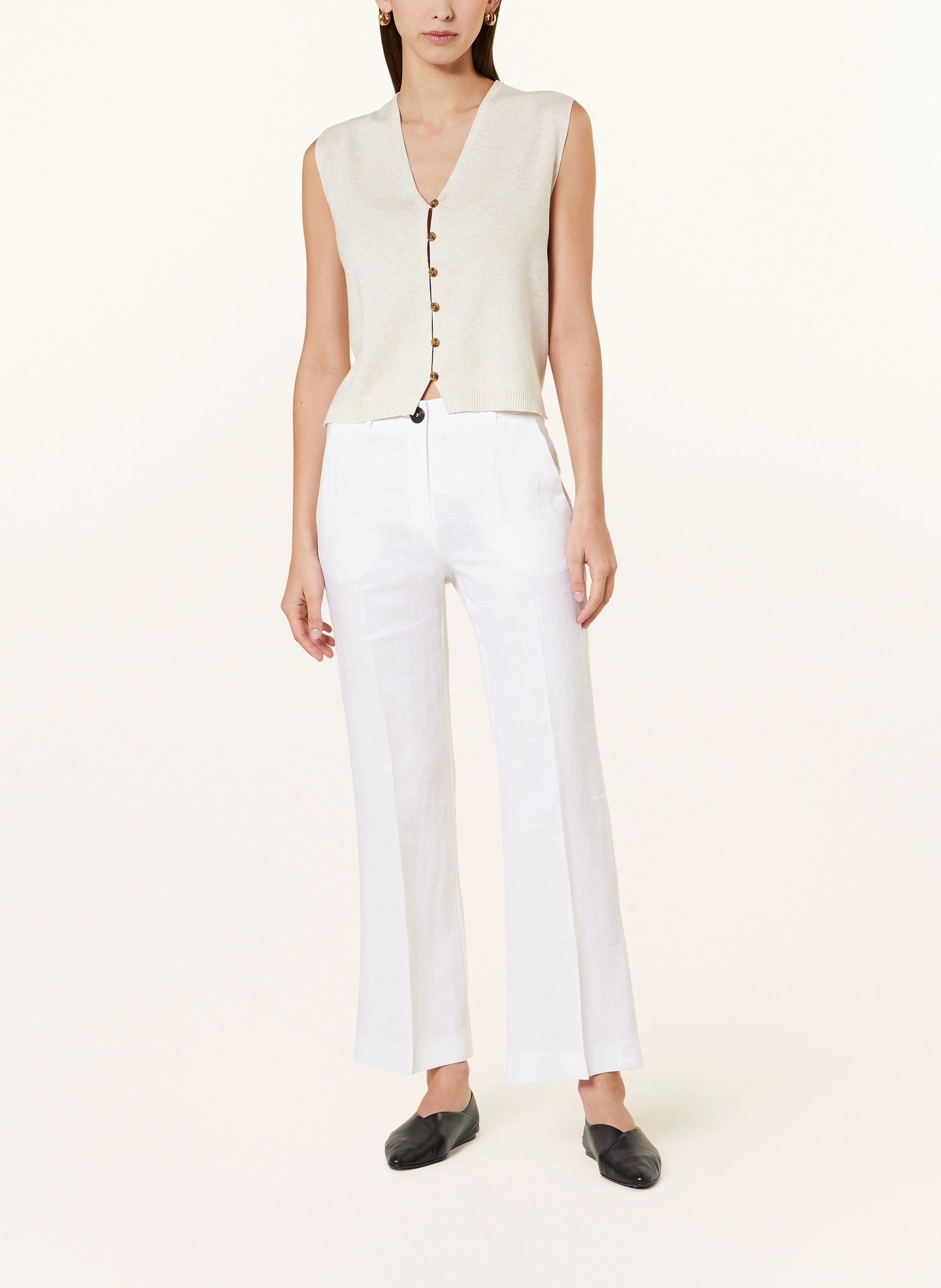 A model wearing high-waisted white linen long trousers with a V-neck top.