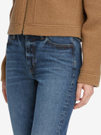 Person wearing blue jeans and a brown jacket on a white background