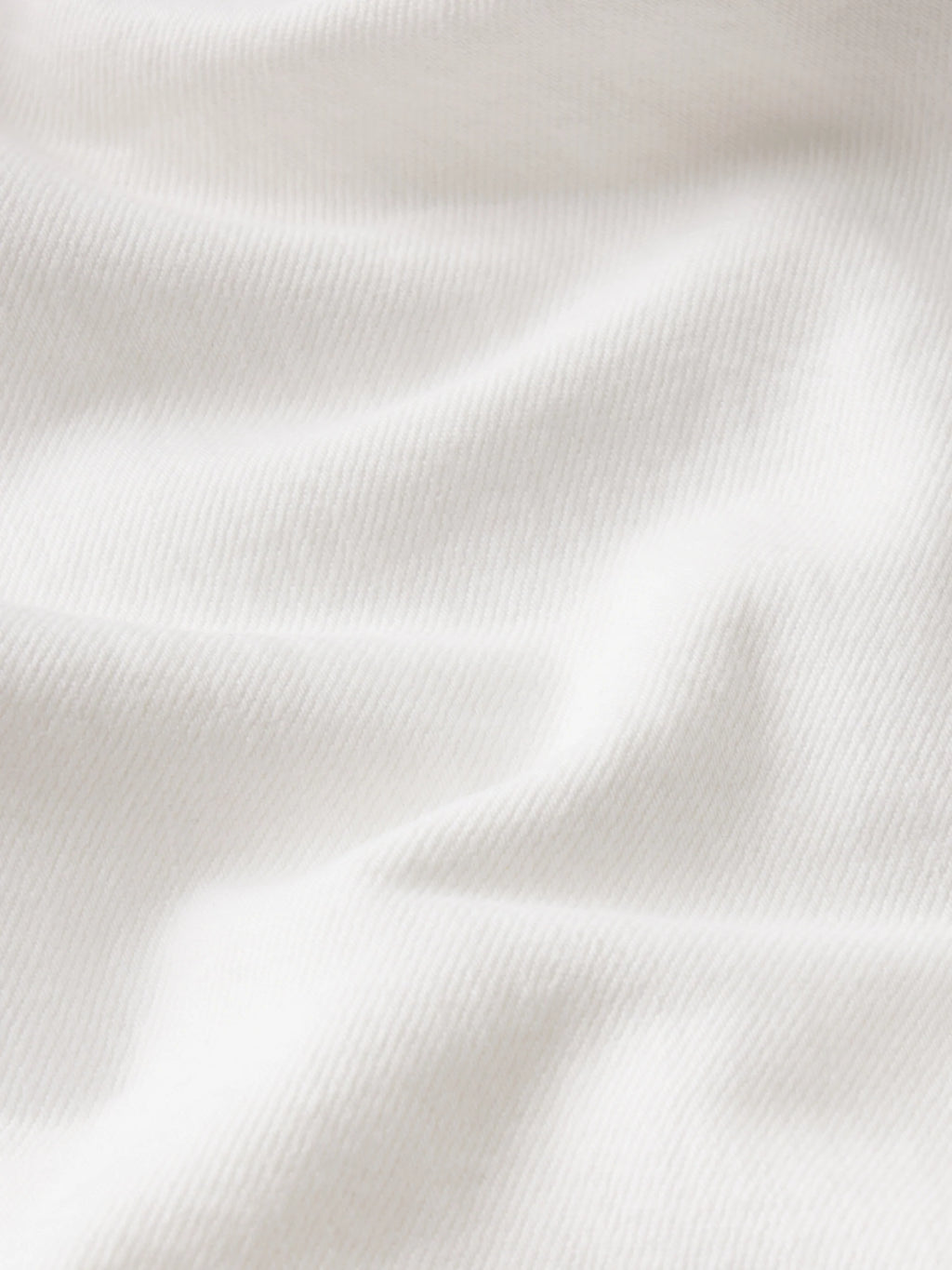 A close-up of softly draped white fabric with visible knit texture and gentle folds.