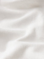 A close-up of softly draped white fabric with visible knit texture and gentle folds.