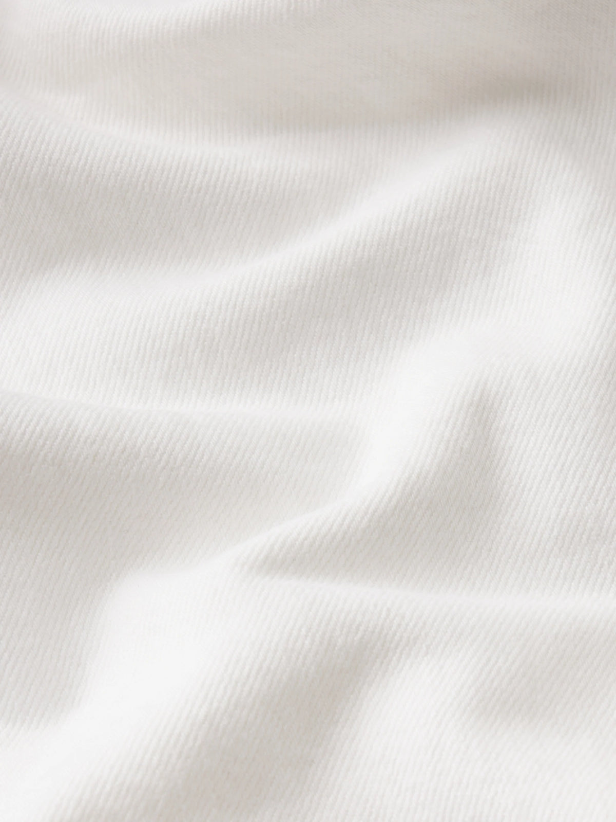 A close-up of softly draped white fabric with visible knit texture and gentle folds.