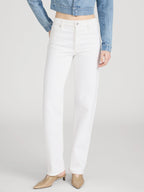 Person wearing white pants and a denim jacket on a plain background