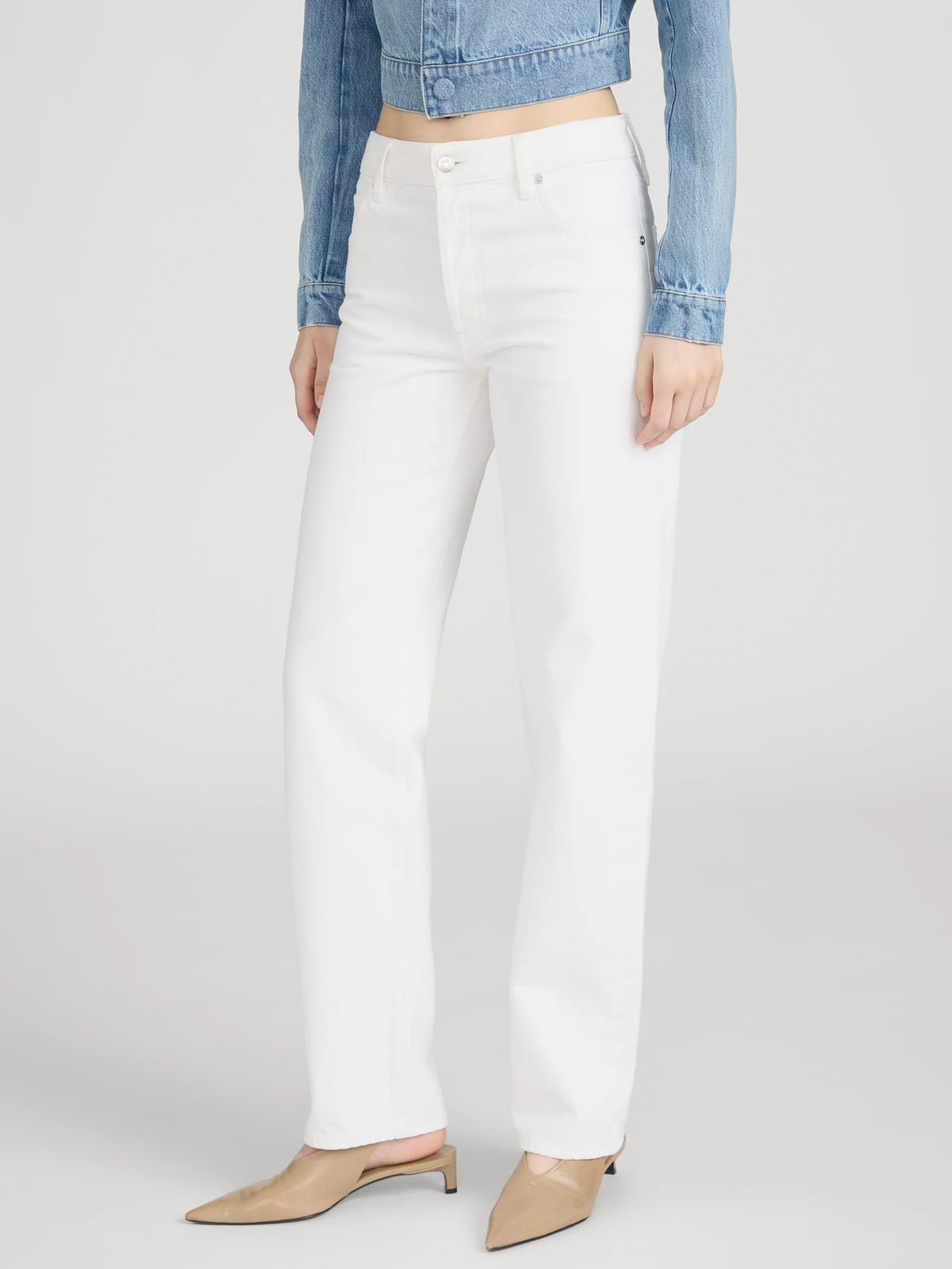 Person wearing white jeans and a denim jacket on a plain background