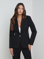 Woman wearing a black suit with a white top against a light gray background