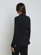 Person wearing a black blazer with gold buttons on a white background