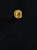 Close-up of a black garment with a gold button featuring a lion emblem.