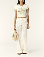 A pair of high-waisted, wide-leg ecru colored pants with a drawstring waist, featuring a lace-look pattern.