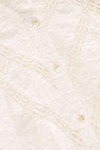 Close-up of a textured white fabric with button details