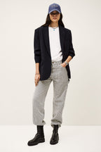 Person wearing a black blazer, white shirt, gray pants, and black shoes on a white background