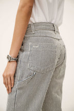 Person wearing black and white striped pants with a plain background