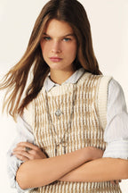 A woman wearing a beige and brown striped sleeveless vest over a white shirt with a collar.