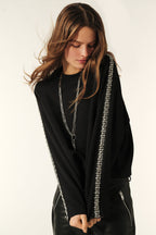 A woman wearing a black top with diamanté bands on the sides, featuring long sleeves and a high neck.