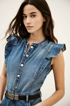 Woman wearing a denim dress with ruffled shoulders against a plain background