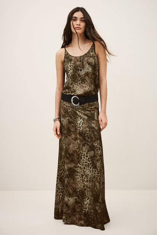 Woman wearing a long, patterned dress with a belt on a plain background