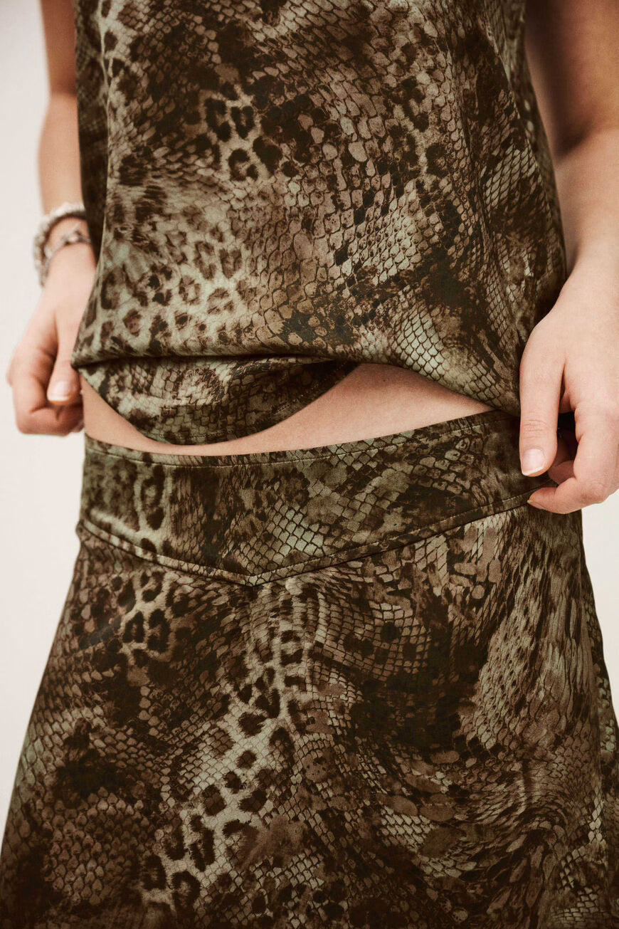 Close-up of a person wearing a patterned outfit with snake and leopard print.
