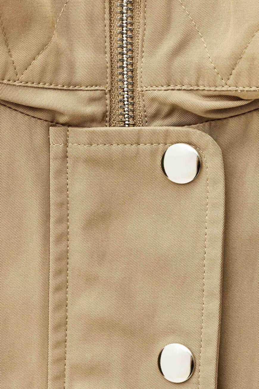 Close-up of a beige jacket with buttons and a zipper