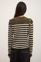 Person wearing a green and white striped sweater with button details on a plain background