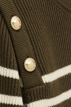 Close-up of a brown ribbed sweater with gold buttons and white stripes.
