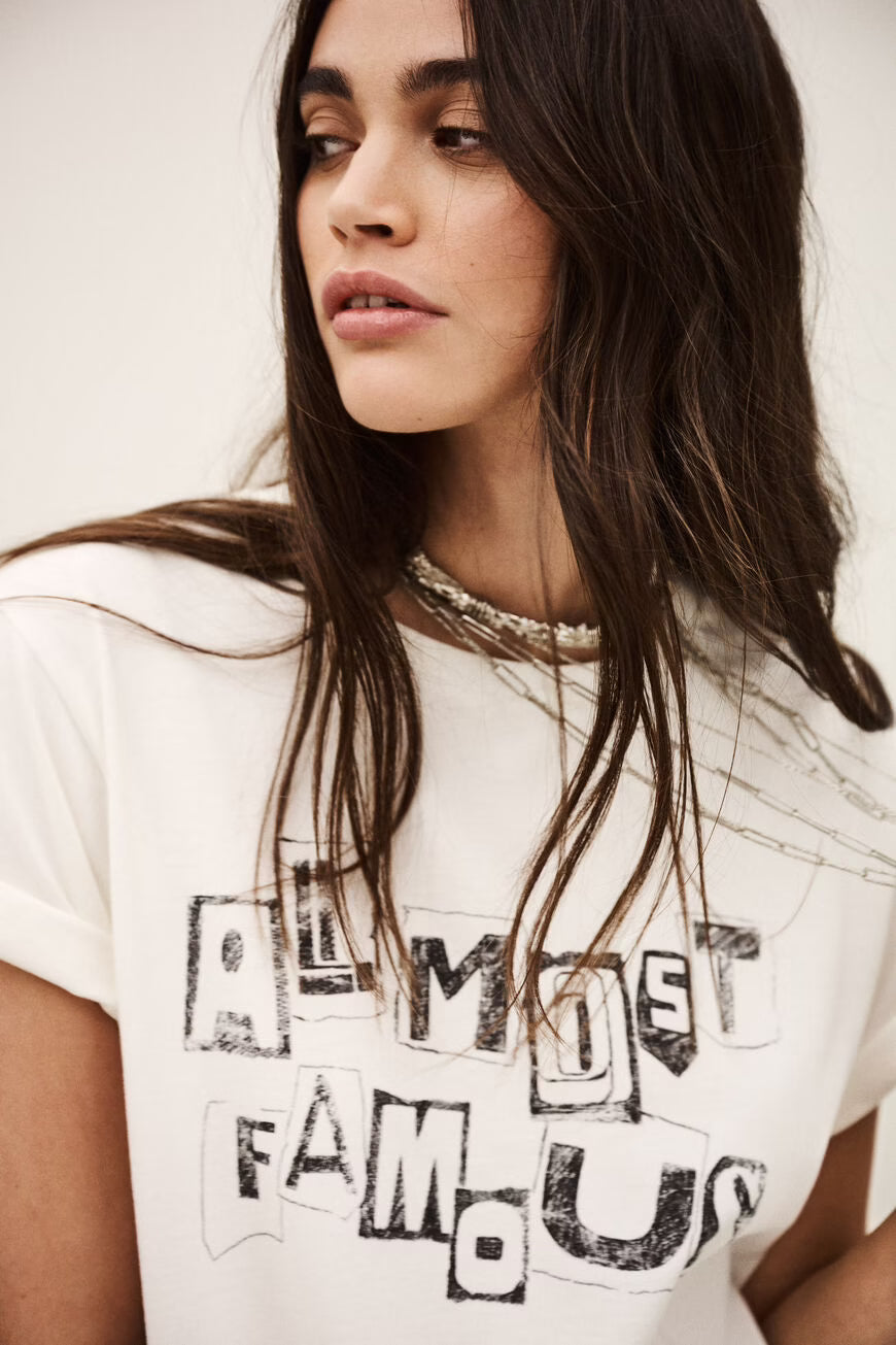 Woman wearing a white t-shirt with text design against a plain background