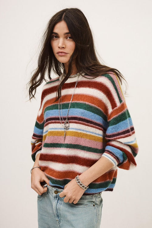 Woman wearing a colorful striped sweater against a white background