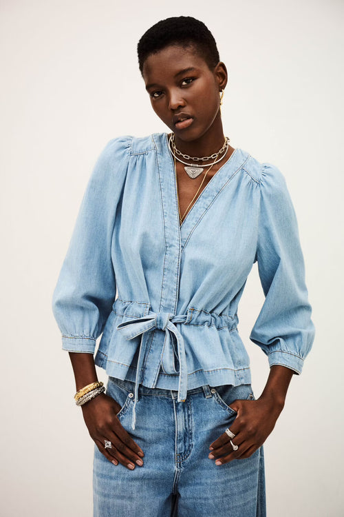 Woman wearing a light blue denim outfit with a white background
