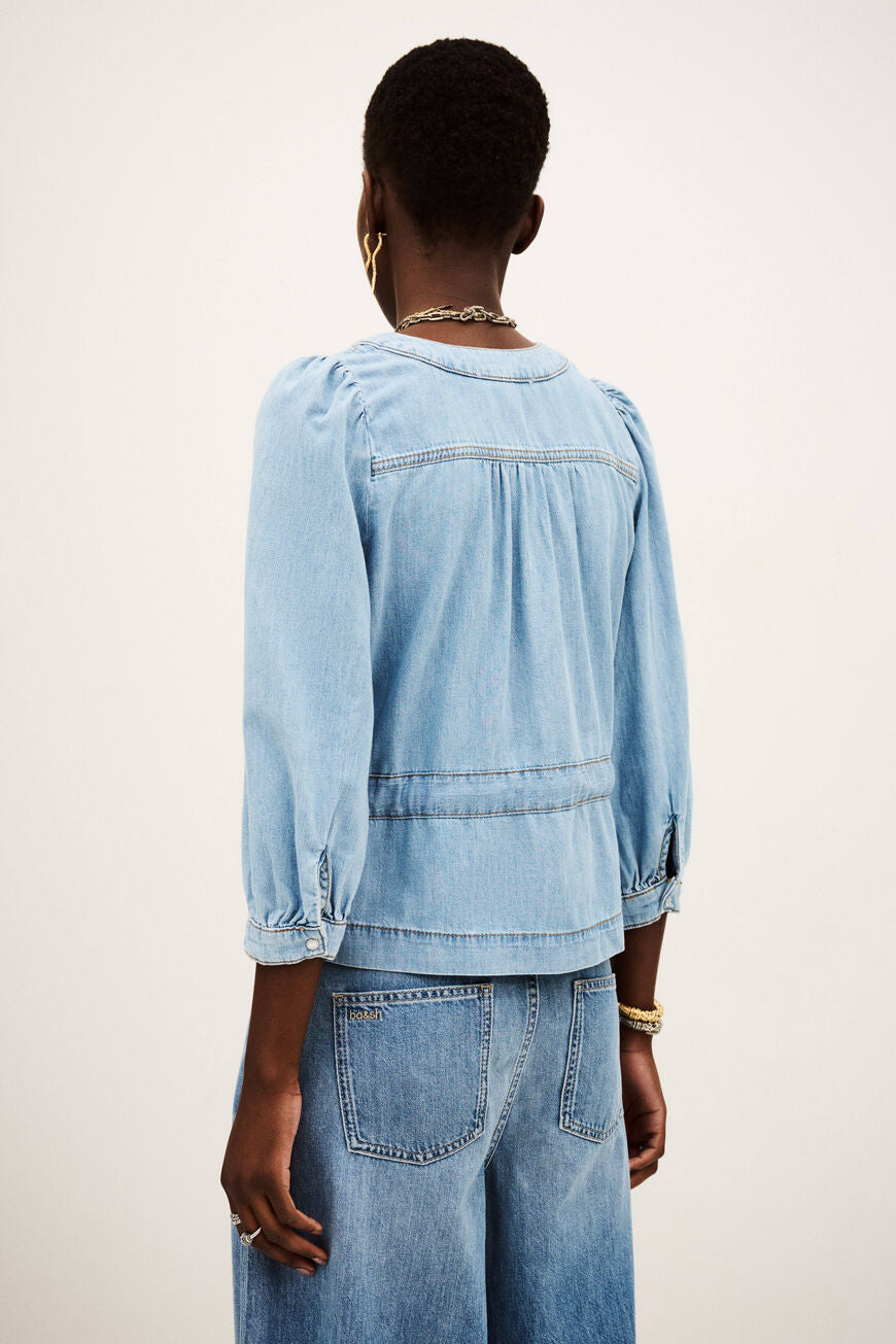 Person wearing a light blue denim jacket and pants on a white background